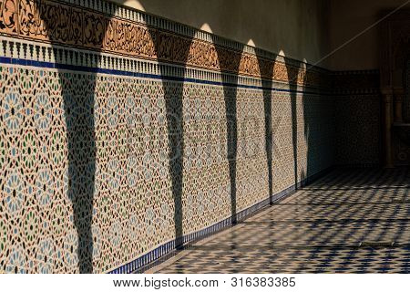 Shadows Of Pillars On A Mosaic Tiled Wall In Full Sunshine