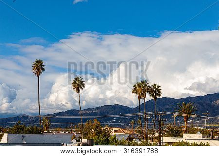 Glendale Building, Homes And Hillside Leading To San Gabriel Mountains, With Blue Sky And Towering C