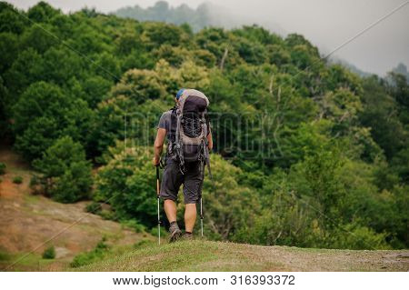 Male Tourist With Backpack Walks In Valley