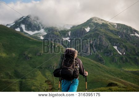 Male Tourist Stands In Front Of Mountains