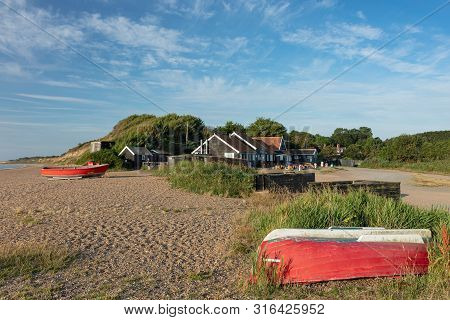 Dunwich, England, Uk - August 8, 2019: Red Fishing Boats On The Shingle Beach In Front Of The Cafe A