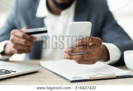 Online Payment. Unrecognizable African Man Holding Credit Card And Using Smartphone For Shopping In 