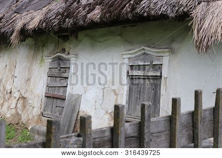 Fragment Of Old Ukrainian Traditional House With Straw Roof, White Clay Walls And Wooden Windows. Hi