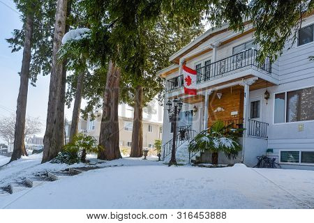 Duplex House On Snowy Day In Winter With Canadian Flag Above The Entrnace