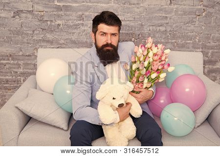 Romantic Man With Flowers And Teddy Bear Sit On Couch Waiting Girlfriend. Romantic Gift. Macho Getti