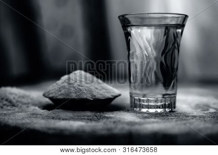 Rice Water In A Glass Bowl Along With Rice Grains & Its Powder Also On Wooden Surface & Some Rice Po