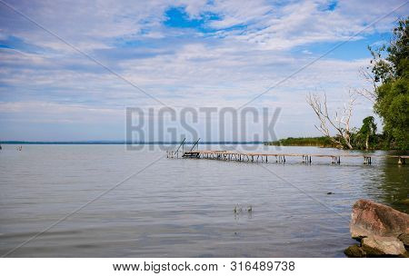 Empty Wood Deck At Balaton Lakeshore In The Morning Hours With Cloudy Sky.