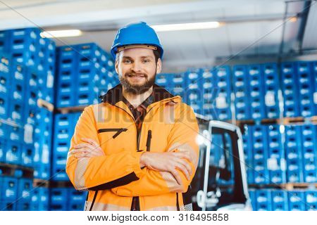 Worker in a forwarding company with his forklift looking into the camera