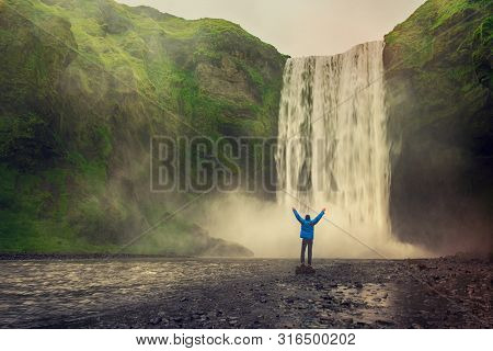 Single Man Standing Near Scogafoss Waterfall In Iceland And Spread His Hands. Travel Summer Nordic C