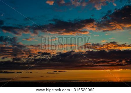 Evening Sky At Sunset Background. Dark Clouds Hanging Above Horizon. Majestic Cloudscape In Blue, Or