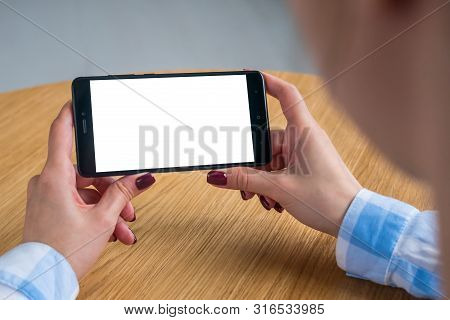 Mockup Image: Woman Looking At Black Smartphone With White Blank Screen. Close Up View Of Woman Hand