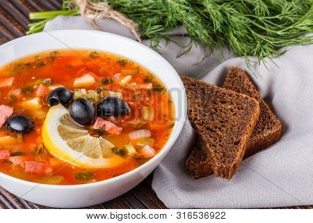 Traditional Russian Meat Soup Solyanka In Bowl On Rustic Wooden Table