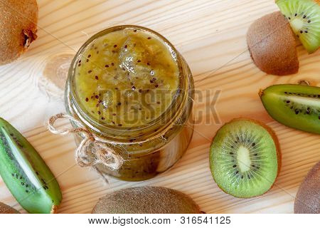 Top View Handmade Green Healthy Kiwi Jam Glassjar With Raw Tropical Fruits On Wooden Table Backgroun