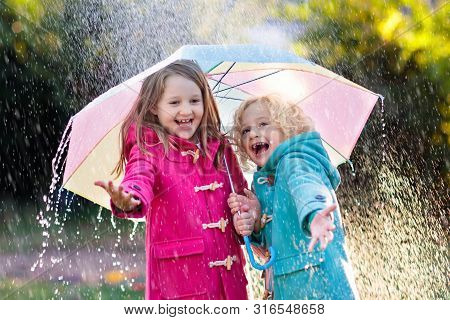 Kids With Umbrella Playing In Autumn Shower Rain.