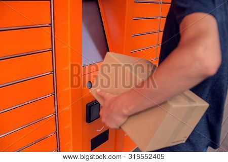 Client Using Automated Self Service Post Terminal Machine Or Locker To Deposit A Parcel For Storage