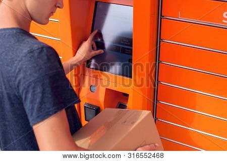 Client Using Automated Self Service Post Terminal Machine Or Locker To Deposit A Parcel For Storage