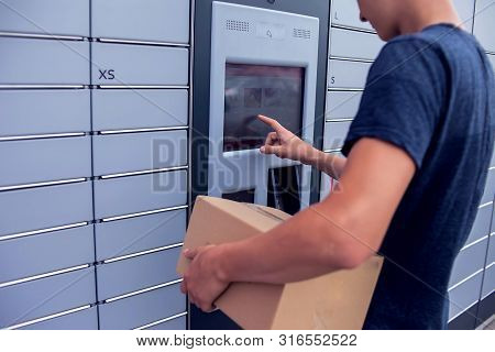 Client Using Automated Self Service Post Terminal Machine Or Locker To Deposit A Parcel For Storage