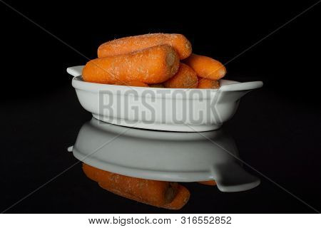 Lot Of Whole Stale  Orange Stale Baby Carrot Baby In A Wooden Bowl Isolated On Black Glass