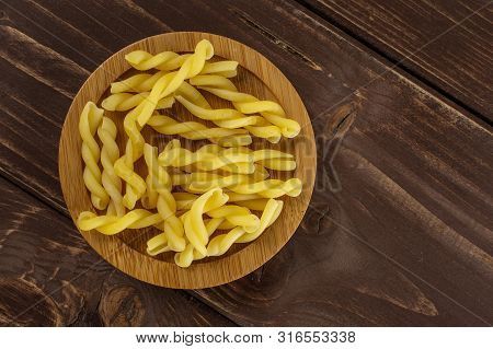 Lot Of Whole Raw Pasta Gemelli On Bamboo Plate Flatlay On Brown Wood
