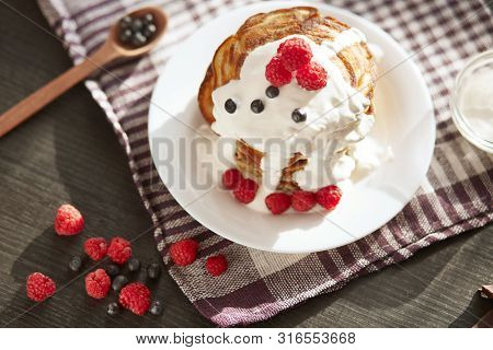 Top Wiev Of Tasty Pancakes On Checkered Cotton Towel, Muffins With Sour Cream, Fresh Blueberries And