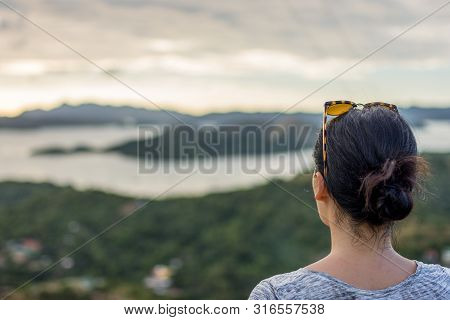 Rear View Of A Young Woman Wearing A Back Pack Looking Over A Cliff And Sea View.