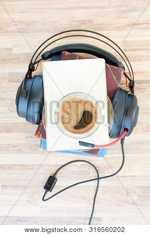 Audio Book Concept. Black Headphones With Books And Cup Of Black Fresh Coffee On Wooden Table. Top V