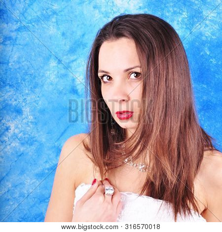 Dark-haired Girl In Exclavant Earrings And A Necklace On An Abstract Background.