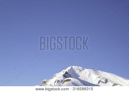 Some Flying Ballons In A Blue Sky Over The Snowy Mountain In The Alps