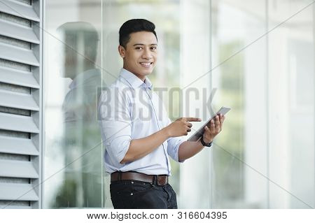 Portrait Of Handsome Young Asian Businessman Standing Outside The Office Building And Ucing Aplicati