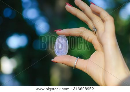 Female Hand With Transparent Amethyst Quartz Yoni Egg For Vumfit, Imbuilding Or Meditation. Shining 