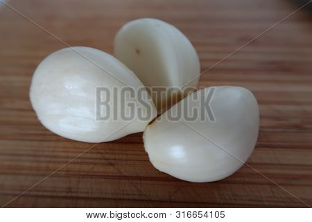 Peeled Fresh Garlic On A Wooden Chopping Board As An Ingredient For Thai Cuisine
