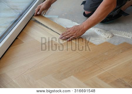 Worker Laying Parquet Flooring. Worker Installing Wooden Laminate Flooring