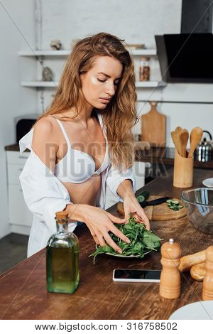 Sexy Woman In White Bra Cooking Salad In Kitchen