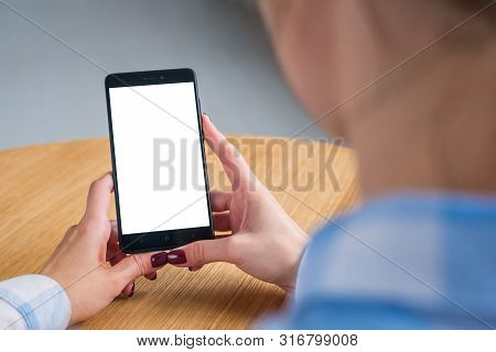 Mockup Image: Woman Looking At Black Smartphone With White Blank Screen. Close Up View Of Woman Hand