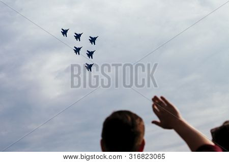 Group Of People Is Looking On The Aerobatic Team Demonstration Flight In A Cloudy Sky, Isolated On G