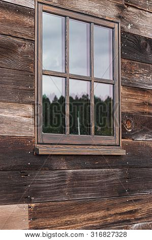Large Window On A Wooden Building Reflecting The Sky On A Cloudy Overcast Day