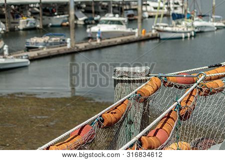 Fishing Net With Bouys Hang In Front Of Harbor Town