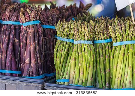 Large Bundles Of Freshly Harvested Asperagus From Local Farms In A Stand In A Market