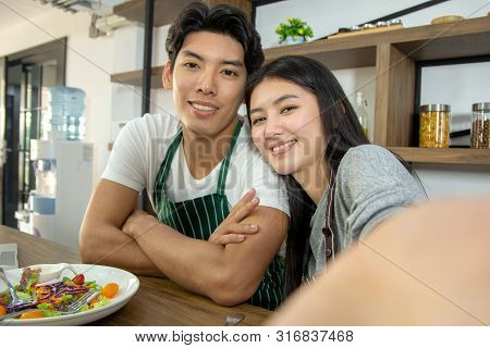 Portrait Of Cute Happy Couple In Aporn In Selfie Action Posting With Mobile Phone Decorated With Sal