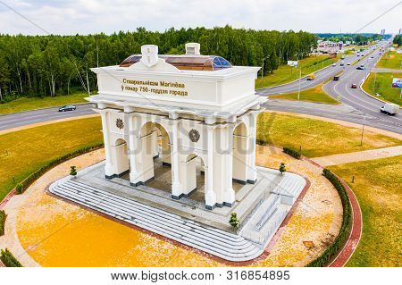 Mogilev, Belarus - June 22, 2019: White Arch Set Up In Middle Of Roundabout. Cars Driving Along Road