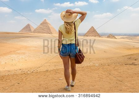 Young Girl In The Desert. Back View Portrait Of A Single Woman Watching The Great Pyramids Of Giza I