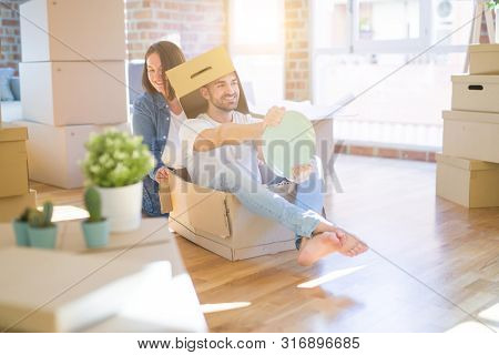 Funny and crazy couple having fun riding a cardboad box as a car, smiling happy and lauging at new home