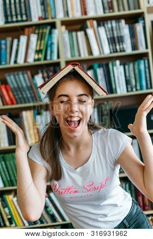 Back To School Library Background With Copy Space. Portrait Of An Excited Happy Student Girl Holding