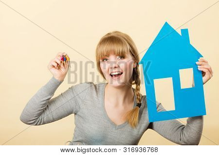 Ownership And Property Concept. Young Blonde Smiling Female Owner With Bunch Of Colorful Keys And Ho
