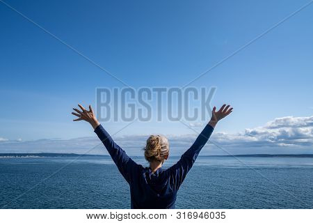 Woman Passenger On The Port Townsend Ferry In Washington State Stands With Her Arms Up And Back To T