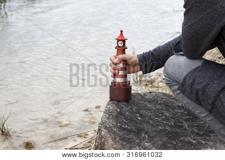 The Young Man Puts On A Stone A Toy Lighthouse Like Gulliver.