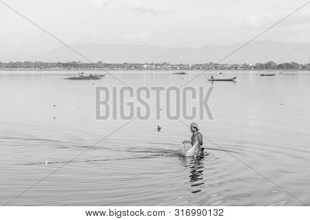 Mandalay, Myanmar - 03 December, 2018: Black And White Picture Of Local Burmese Fisherman Fishing Wi