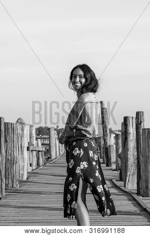Black And White Picture Of Happy Brunette Woman Posing At Wooden U Bein Bridge, Which Is A Touristic
