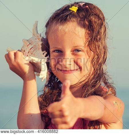 Child put the shell to her ear. Summer vacation. Girl on sea background