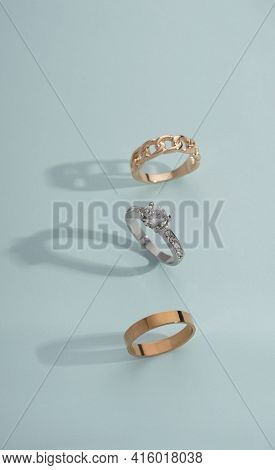 Vertical Shot Of Three Golden Rings On Boue Background With Copy Space